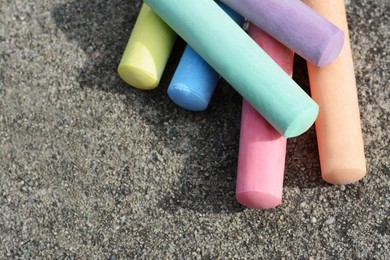 Photo of Many colorful chalk sticks on asphalt, above view. Space for text