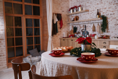 Dining table with red cups and mistletoe flower in kitchen