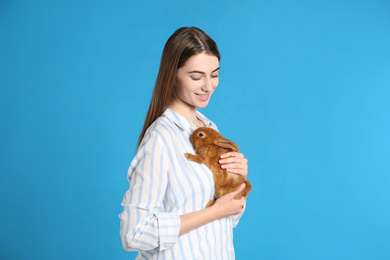 Young woman with adorable rabbit on blue background. Lovely pet