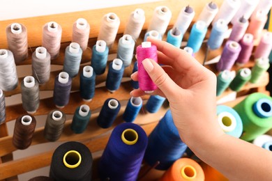 Dressmaker taking pink thread from stand, closeup