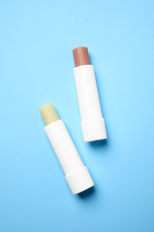 Hygienic lipsticks on light blue background, flat lay