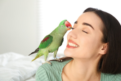 Young woman with Alexandrine parakeet indoors, closeup. Cute pet