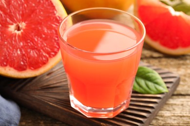 Glass of delicious grapefruit juice on wooden table, closeup
