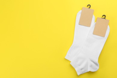 White cotton socks on yellow background, flat lay. Space for text