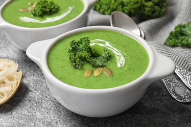 Tasty kale soup with pumpkin seeds on grey table, closeup