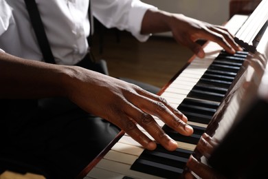 African-American man playing piano indoors, closeup. Talented musician
