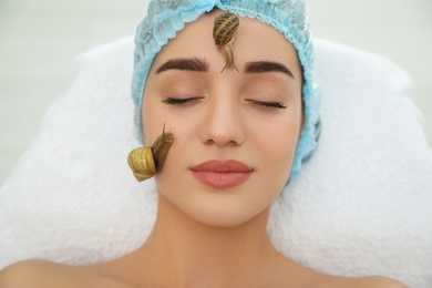 Photo of Young woman receiving snail facial massage in spa salon, closeup