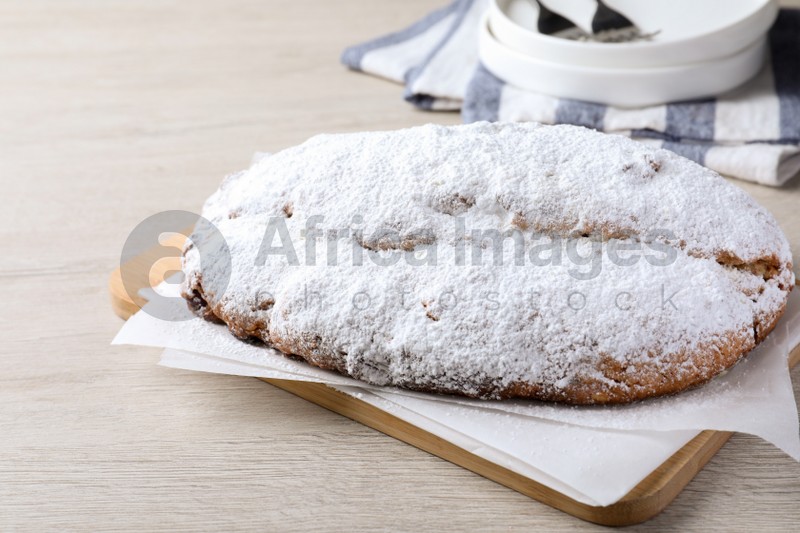 Delicious Stollen sprinkled with powdered sugar on wooden table