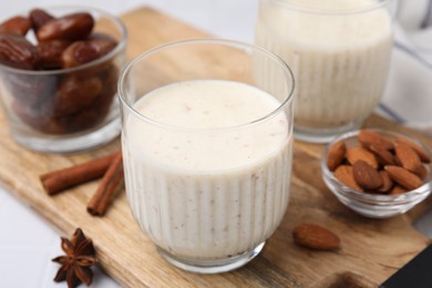 Photo of Glass of delicious date smoothie, dried fruits, spices and nuts on table