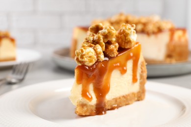 Photo of Piece of delicious caramel cheesecake with popcorn on plate, closeup