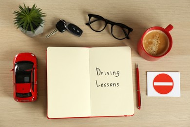 Flat lay composition with workbook for driving lessons and cup of coffee on white wooden background. Passing license exam