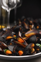 Plate of cooked mussels with parsley on table, closeup
