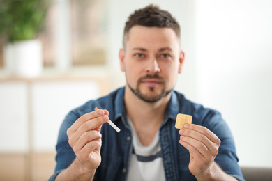Man with nicotine patch and cigarette at home, focus on hands