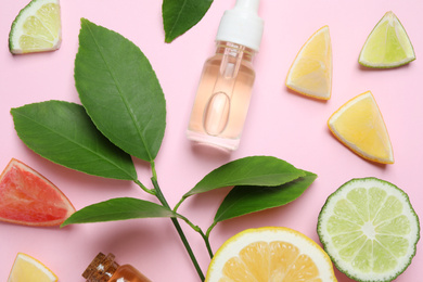 Flat lay composition with bottles of citrus essential oil on pink background