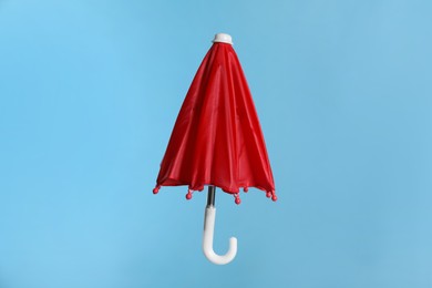 Closed small red umbrella on light blue background