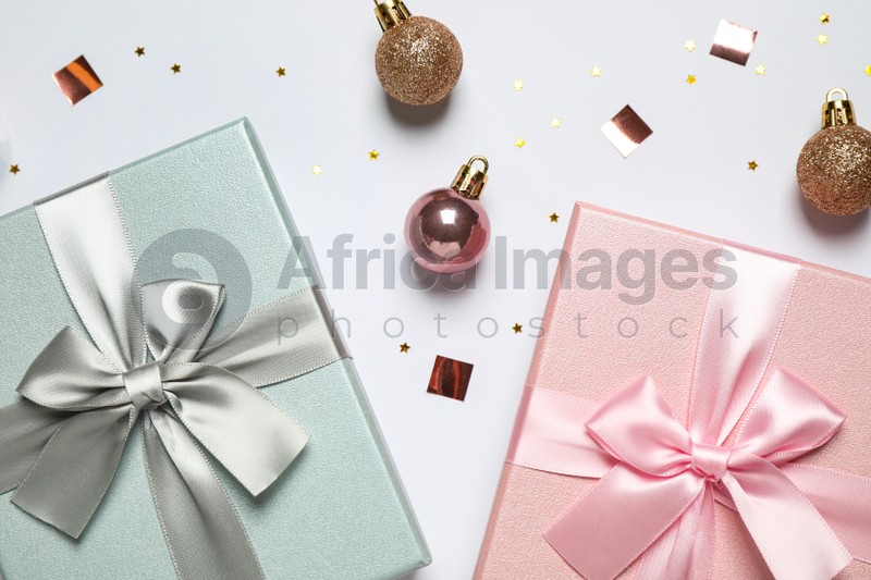Beautiful gift boxes, Christmas balls and confetti on white background, flat lay