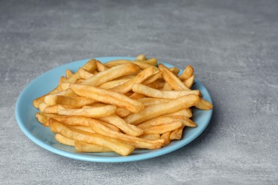 Turquoise plate with delicious french fries on light gray marble table, closeup