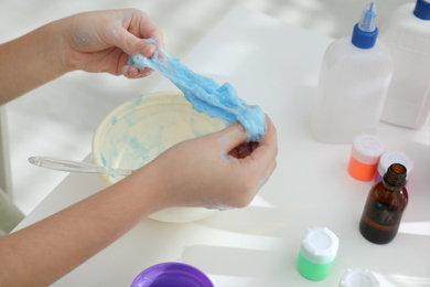 Little girl making DIY slime toy at table, closeup