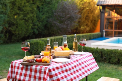 Photo of Table with delicious food and drinks outdoors. Barbecue party