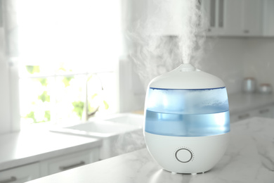 Modern air humidifier on table in kitchen. Space for text