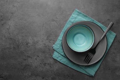 Stylish empty dishware and fork on grey table, top view. Space for text