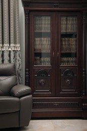 Comfortable armchair near wooden bookcase in library