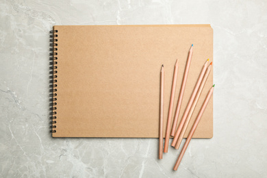 Stylish notebook and pencils on marble table, top view