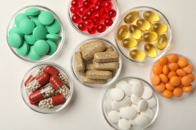 Photo of Different dietary supplements in bowls on white background, flat lay