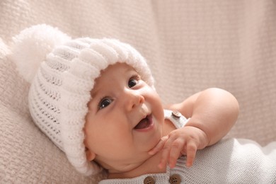 Photo of Cute little baby wearing white warm hat on knitted blanket, closeup