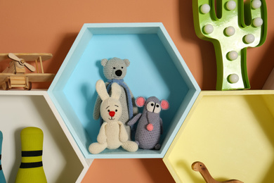 Hexagon shaped shelves with toys on orange wall. Interior design