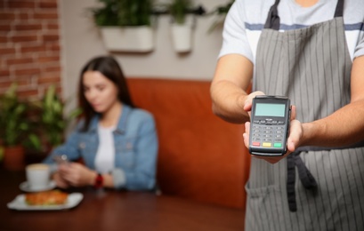 Waiter with payment terminal in cafe, closeup. Space for text