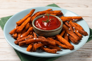 Photo of Delicious sweet potato fries served with sauce on white wooden table, closeup