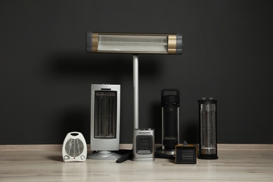 Set of different modern electric heaters near black wall