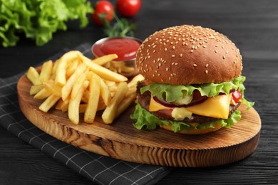 Photo of Delicious burger with beef patty, tomato sauce and french fries on dark table