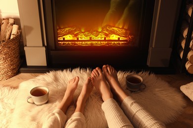 Photo of Couple resting near fireplace at home, closeup of legs