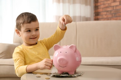 Little boy with piggy bank and money at home