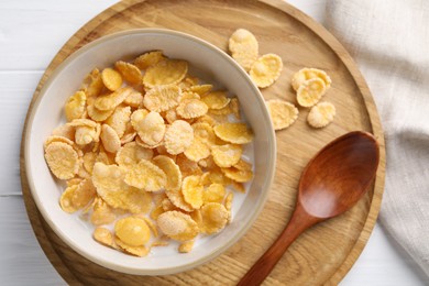 Tasty cornflakes with milk in bowl served on white wooden table, top view