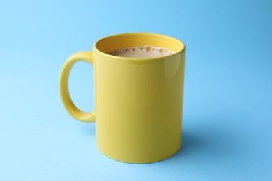 Yellow mug of freshly brewed hot coffee on light blue background