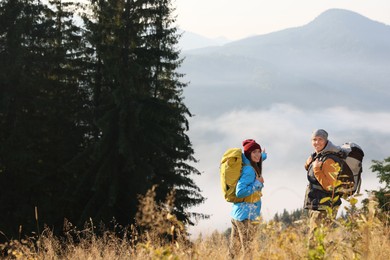 Tourists with backpacks in mountains on sunny day. Space for text
