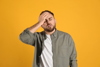 Man suffering from migraine on yellow background