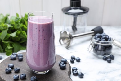 Glass of blueberry smoothie with mint and fresh berries on white marble table. Space for text