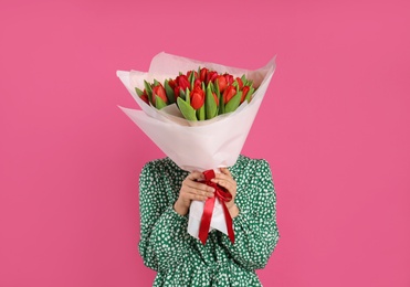 Woman with red tulip bouquet on pink background. 8th of March celebration