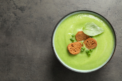 Tasty homemade zucchini cream soup on grey table, top view. Space for text