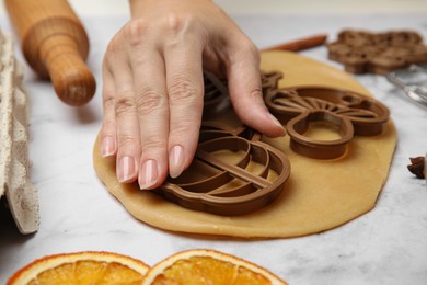 Photo of Woman making biscuits with cookie cutters on white marble table, closeup