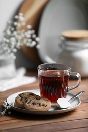 Cup of freshly brewed tea and delicious cookies on wooden table, space for text