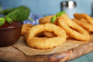 Fried onion rings served on blue wooden table, closeup