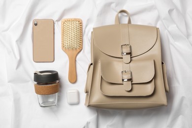 Stylish urban backpack and different items on white fabric, flat lay