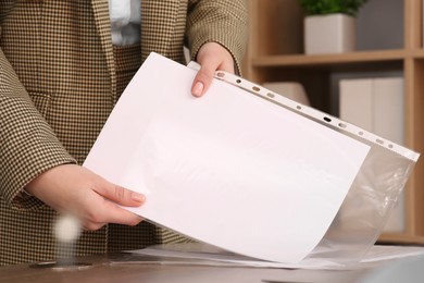 Photo of Businesswoman putting document into punched pocket in office, closeup