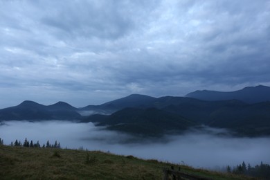 Photo of Picturesque view of mountains covered with fog under cloudy sky