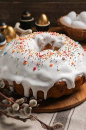 Photo of Delicious Easter cake decorated with sprinkles and willow branches on table